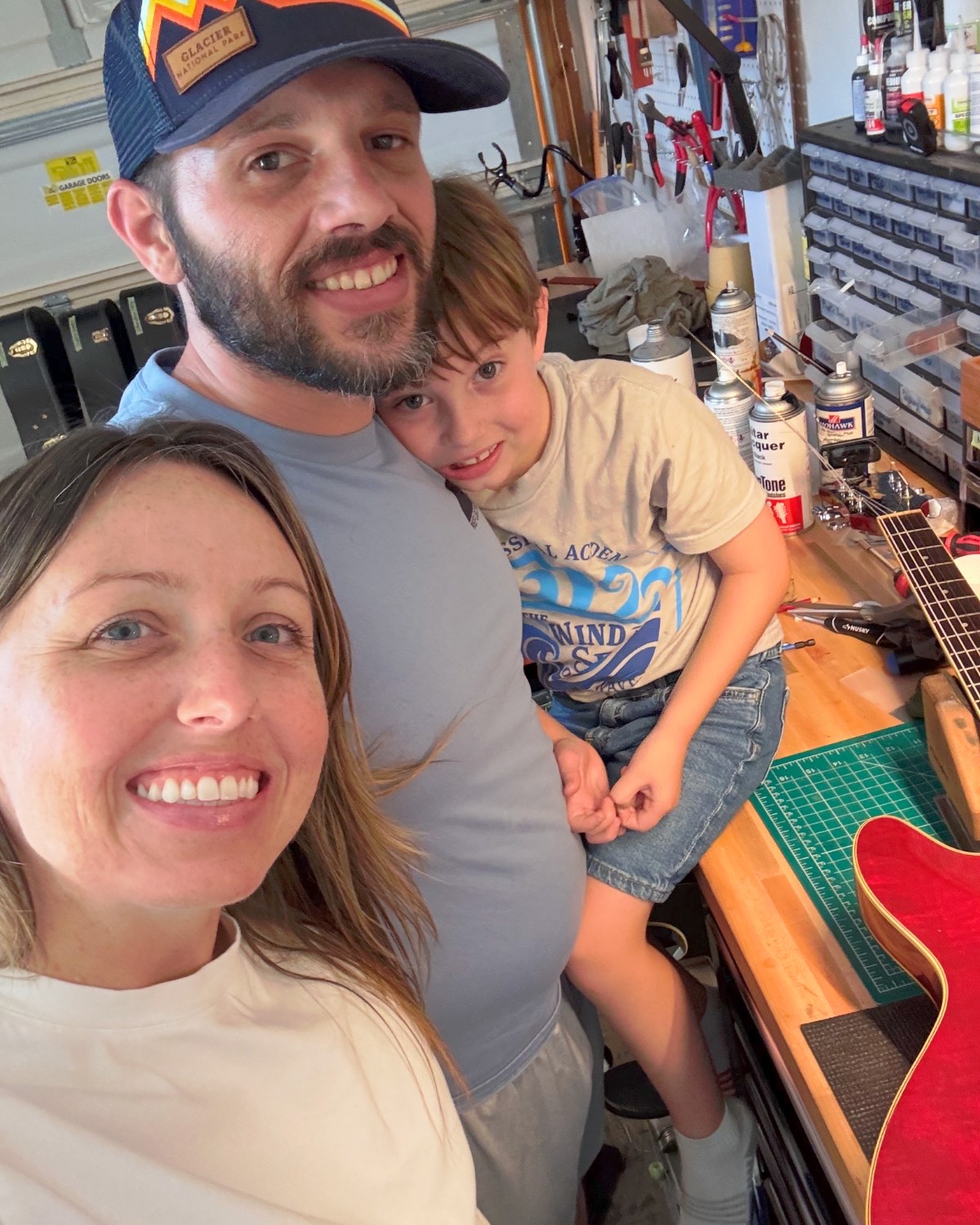 Margie, Josh, and their son at the workbench in the Reflection Guitars shop